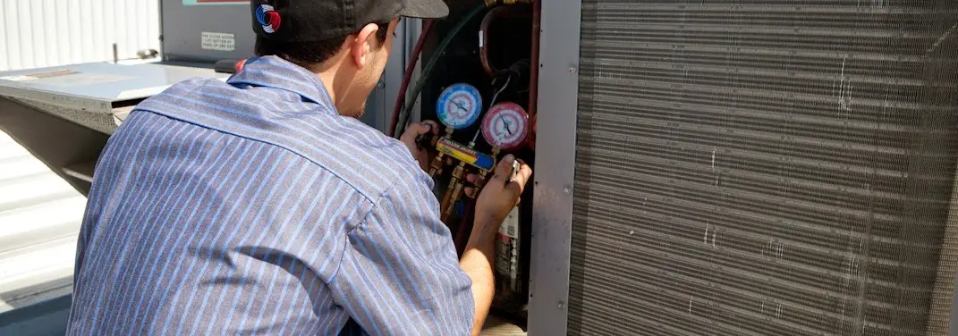 HVAC technician servicing a condenser unit in Clinton